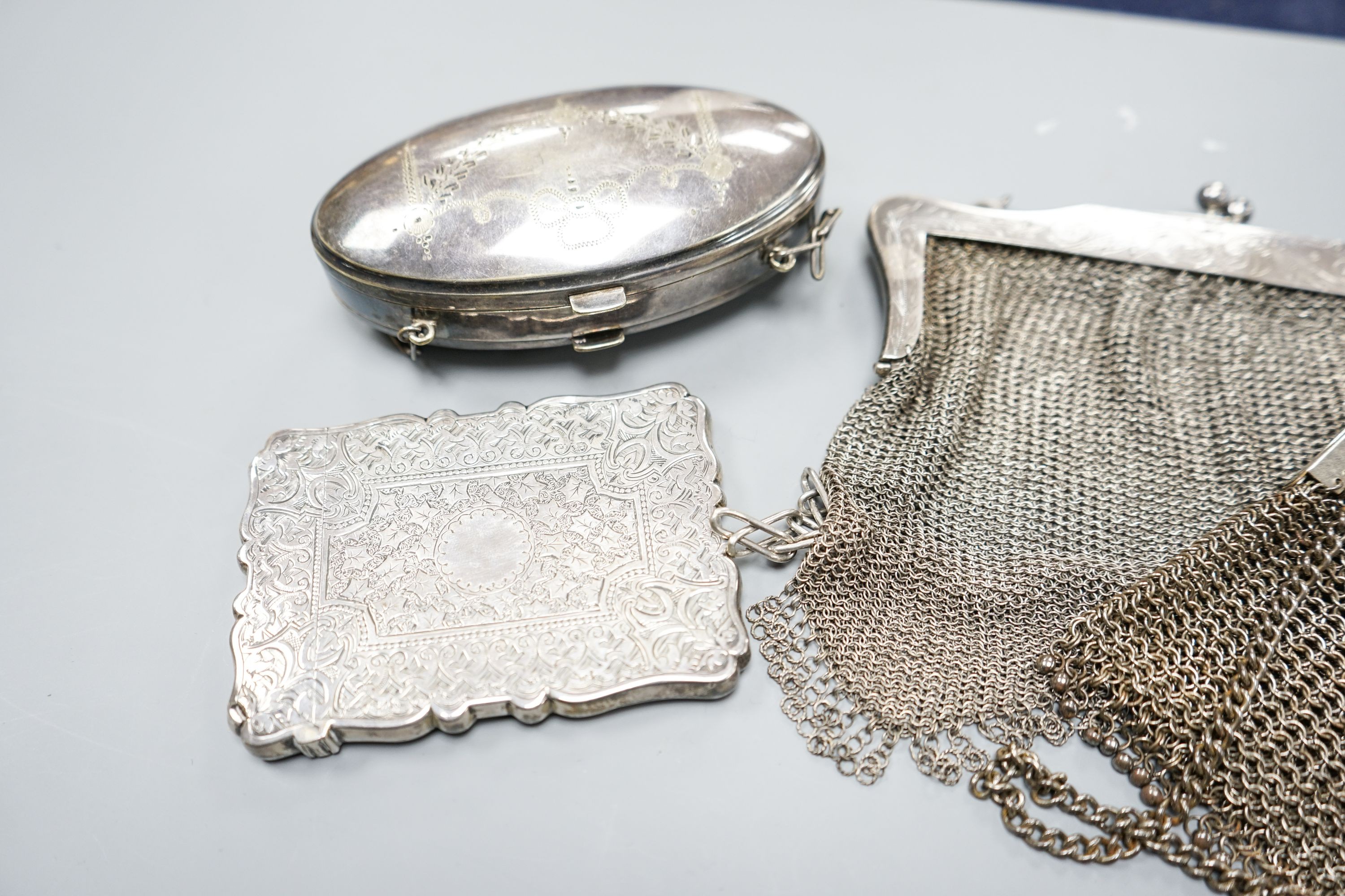 A late Victorian engraved silver card case, Birmingham, 1877, 10cm, a silver mesh evening purse and two other plated items.